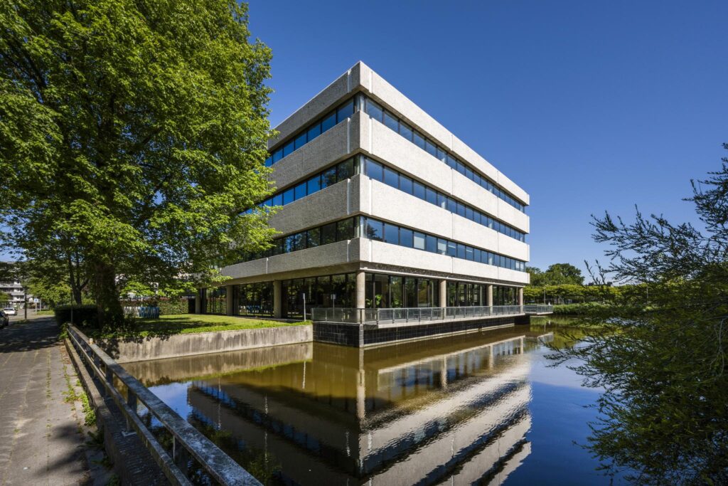 Modern office building on Prof. E.M. Meijerslaan reflected in a canal on a sunny day.
